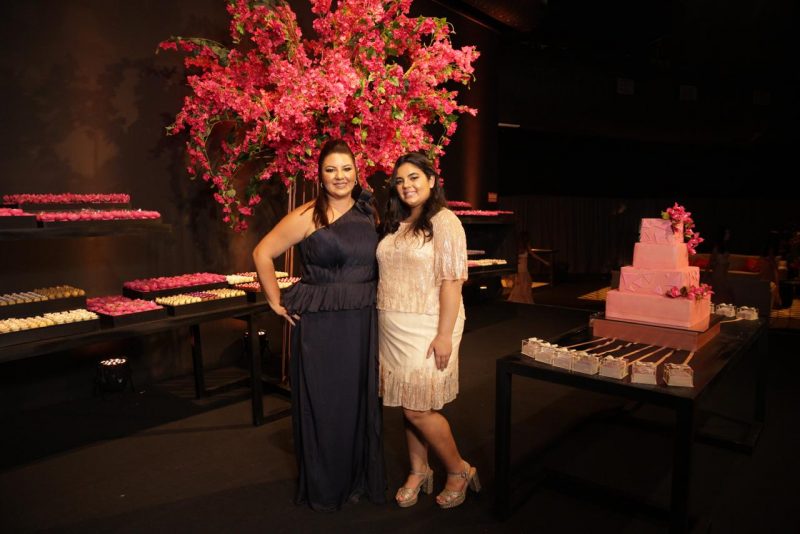 Maria Betânia Tiburcio, que envergou um modelo Lúcia Spessato, ao lado da filha, e com o belo arranjo floral e mesa de doces ao fundo.Foto: Canal R